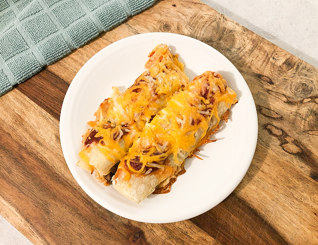 cheesy chicken enchiladas on a white plate